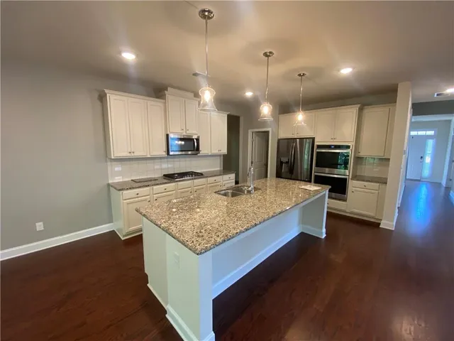 a kitchen with kitchen island a counter top space a sink stainless steel appliances and cabinets