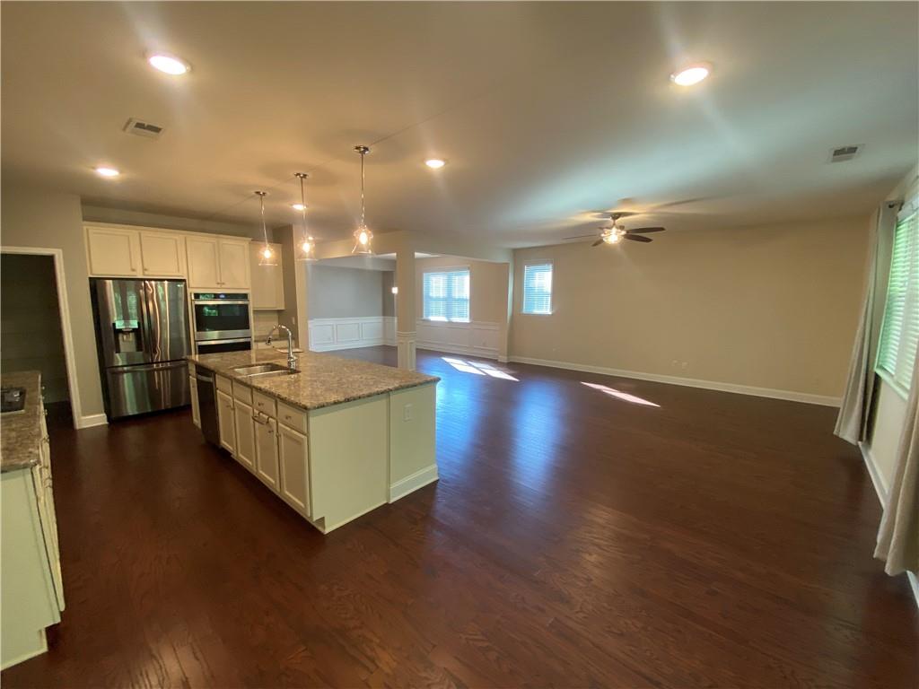 4870 Odum View Lane Cumming, GA 30040 - Photo 4 of 23 a large kitchen with stainless steel appliances a large counter top and a wooden floor