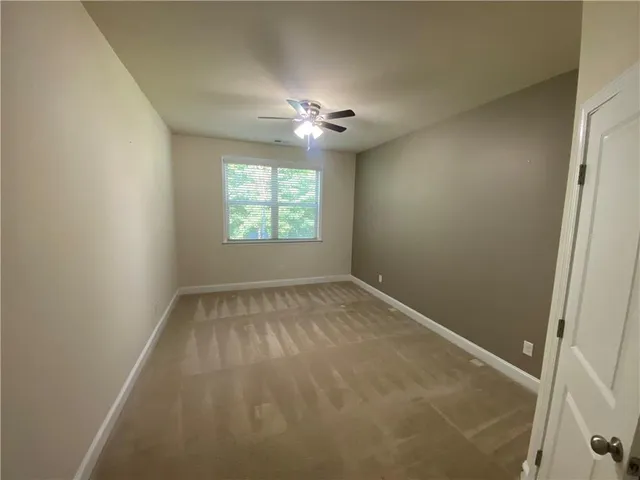 an empty room with windows and ceiling fan