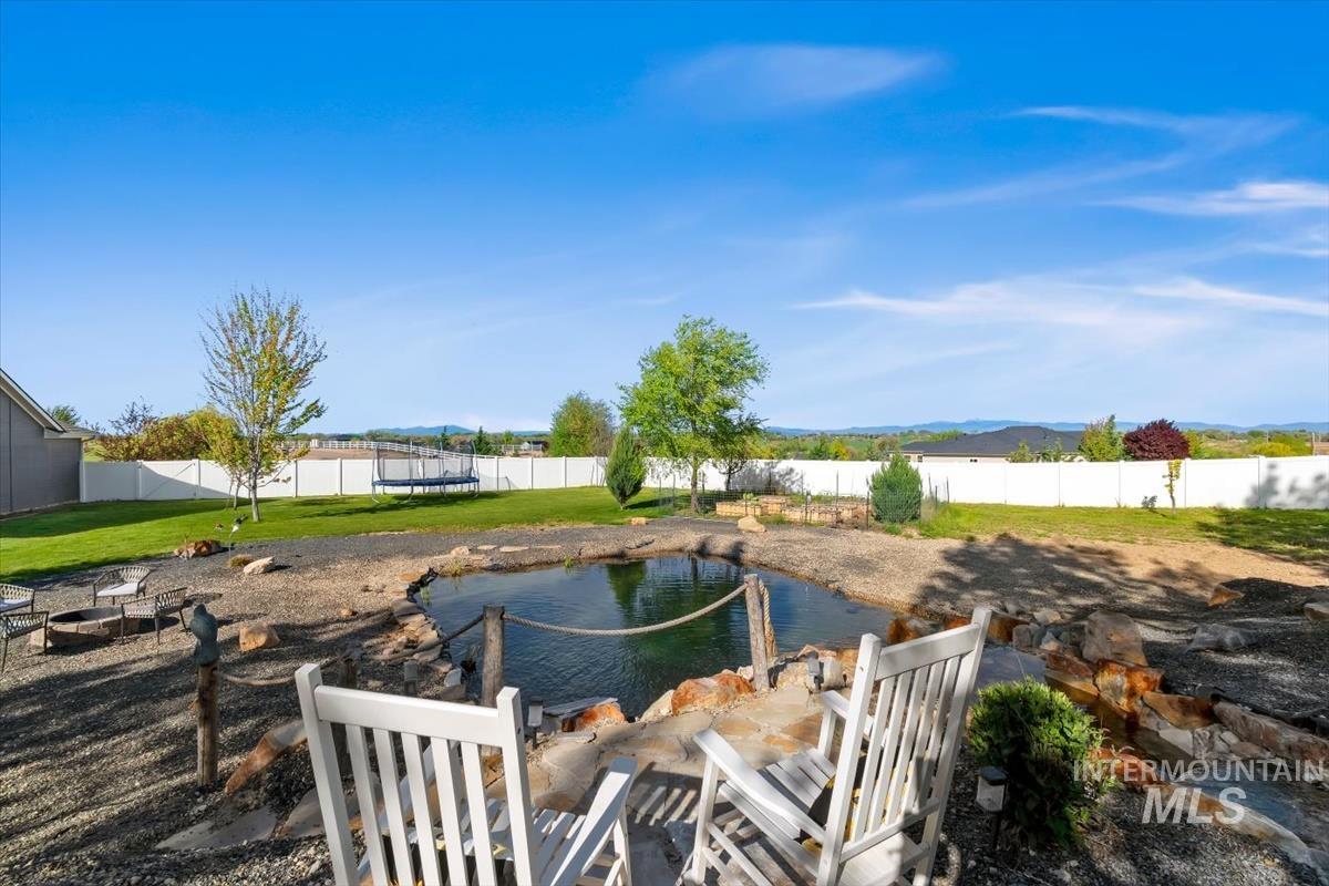15015 Leon Lane Caldwell, ID 83607 - Photo 34 of 44 Expansive backyard featuring a custom pond with stone edging, a gravel-covered patio, and a dedicated fire pit area