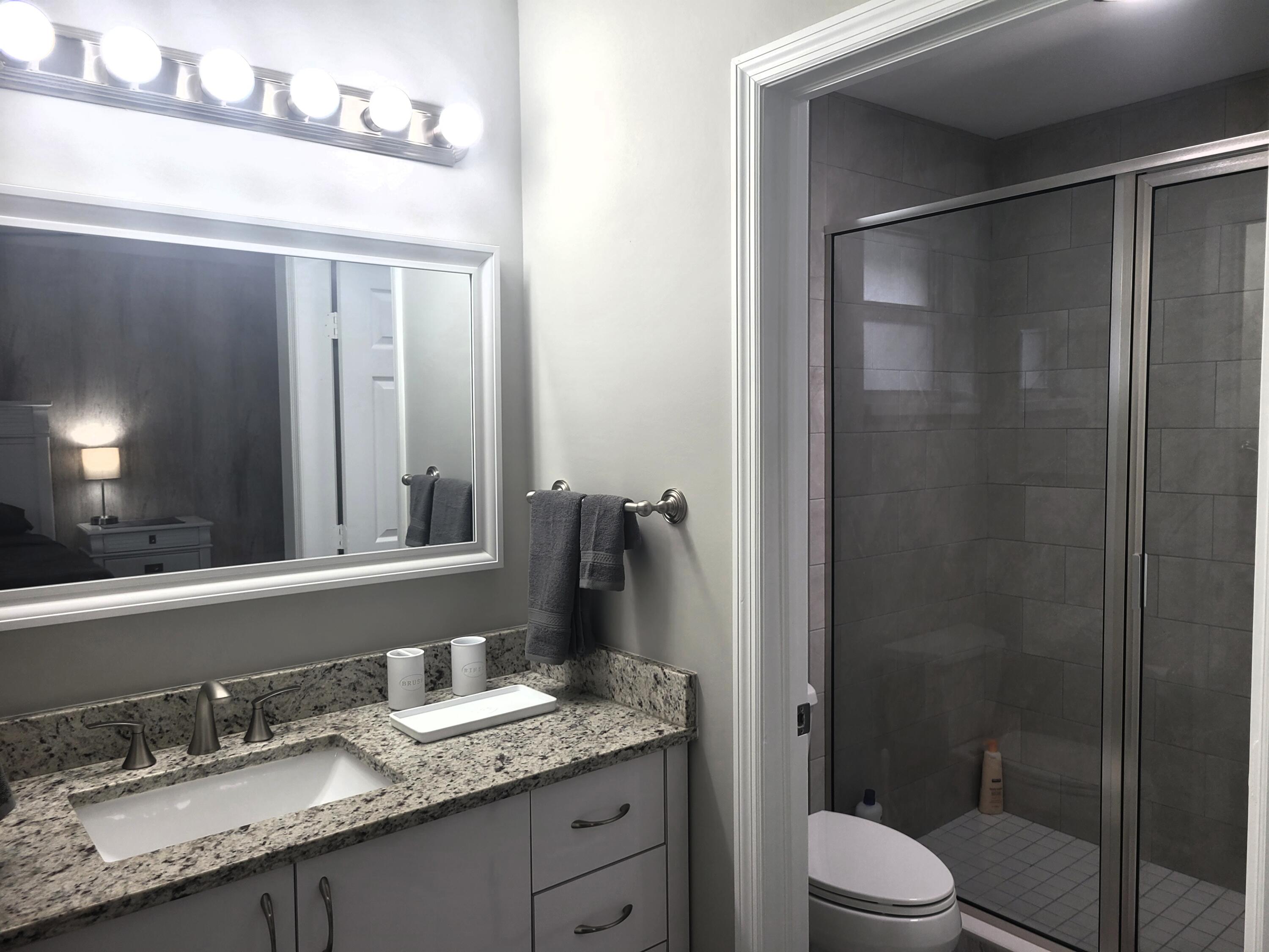 511 West Pine Street, Unit B Lantana, FL 33462 - Photo 8 of 11 a bathroom with a granite countertop sink toilet a mirror a vanity and shower