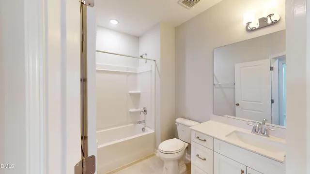 a bathroom with a bathtub shower sink vanity mirror and toilet