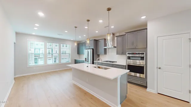 a kitchen with a refrigerator a stove top oven and a sink with wooden floor