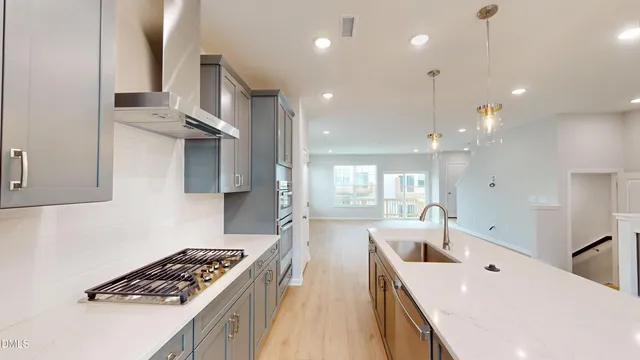 a kitchen with stainless steel appliances kitchen island a white stove top oven a sink dishwasher and a refrigerator with wooden floor