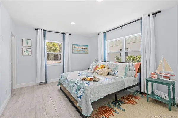 a bed sitting in a bedroom next to a window with wooden floor