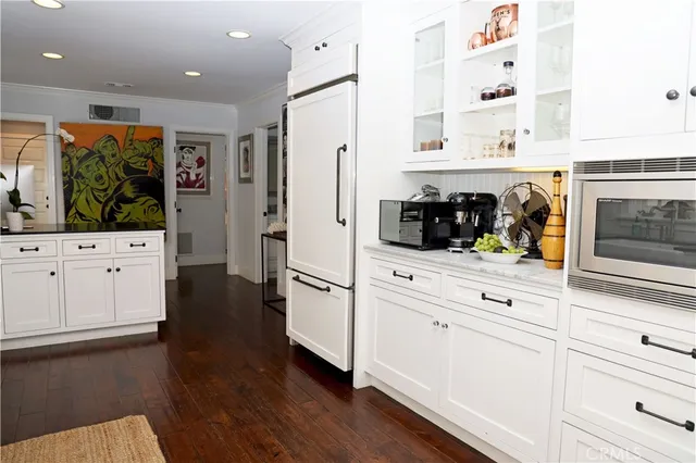 a kitchen with white cabinets and wooden floor