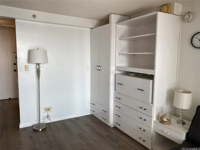 a view of an empty room with cabinet and a lamp