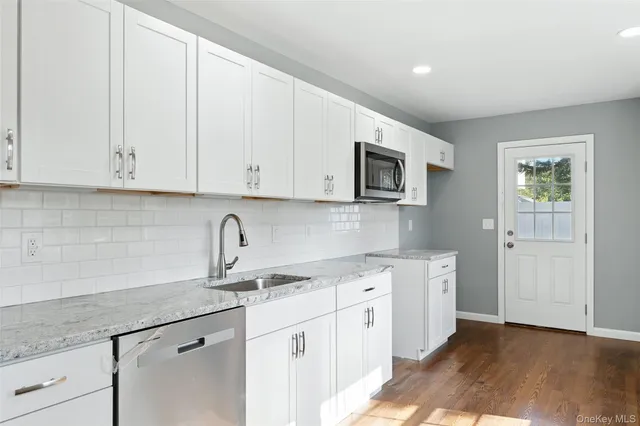 a kitchen with stainless steel appliances granite countertop a sink a stove a microwave and cabinets