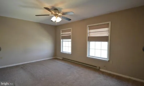 an empty room with windows and chandelier fan