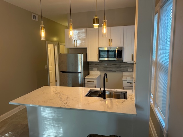 5743 South Emerald Avenue Chicago, IL 60621 - Photo 5 of 28 a kitchen with a refrigerator a microwave a sink and a stove