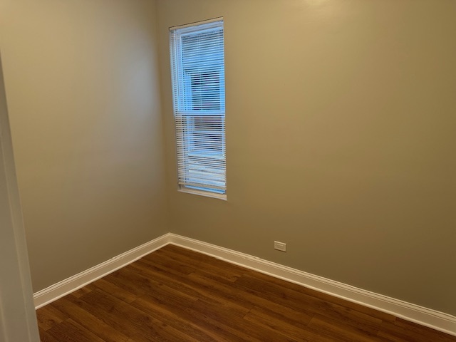 5743 South Emerald Avenue Chicago, IL 60621 - Photo 6 of 28 a view of an empty room with wooden floor and a window