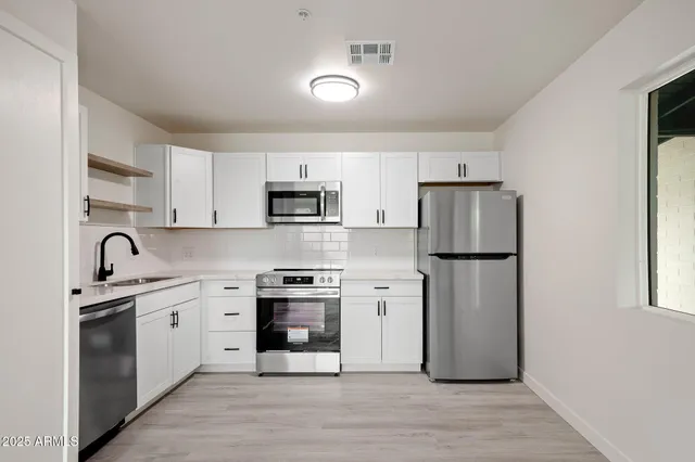 a kitchen with stainless steel appliances cabinets a sink and a refrigerator