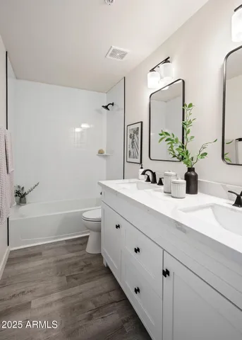 a bathroom with a double vanity sink toilet mirror and bathtub
