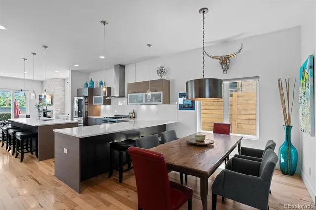 a kitchen with a stove a refrigerator a sink dishwasher a dining table and chairs with wooden floor