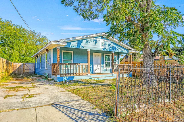a view of a house with a large tree and wooden fence
