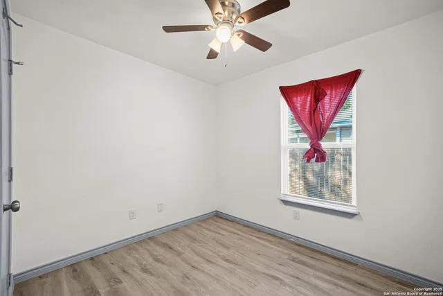 an empty room with windows and fan