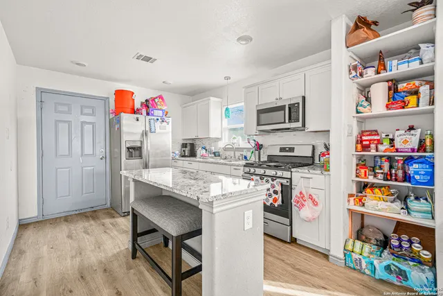 a kitchen with stainless steel appliances granite countertop a refrigerator and a stove top oven