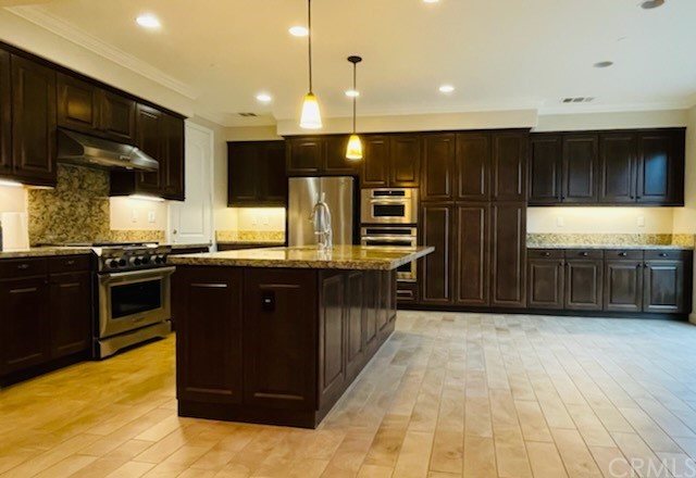 56 Shadowbrook Irvine, CA 92604 - Photo 3 of 20 a kitchen with stainless steel appliances kitchen island granite countertop a stove a sink and a microwave