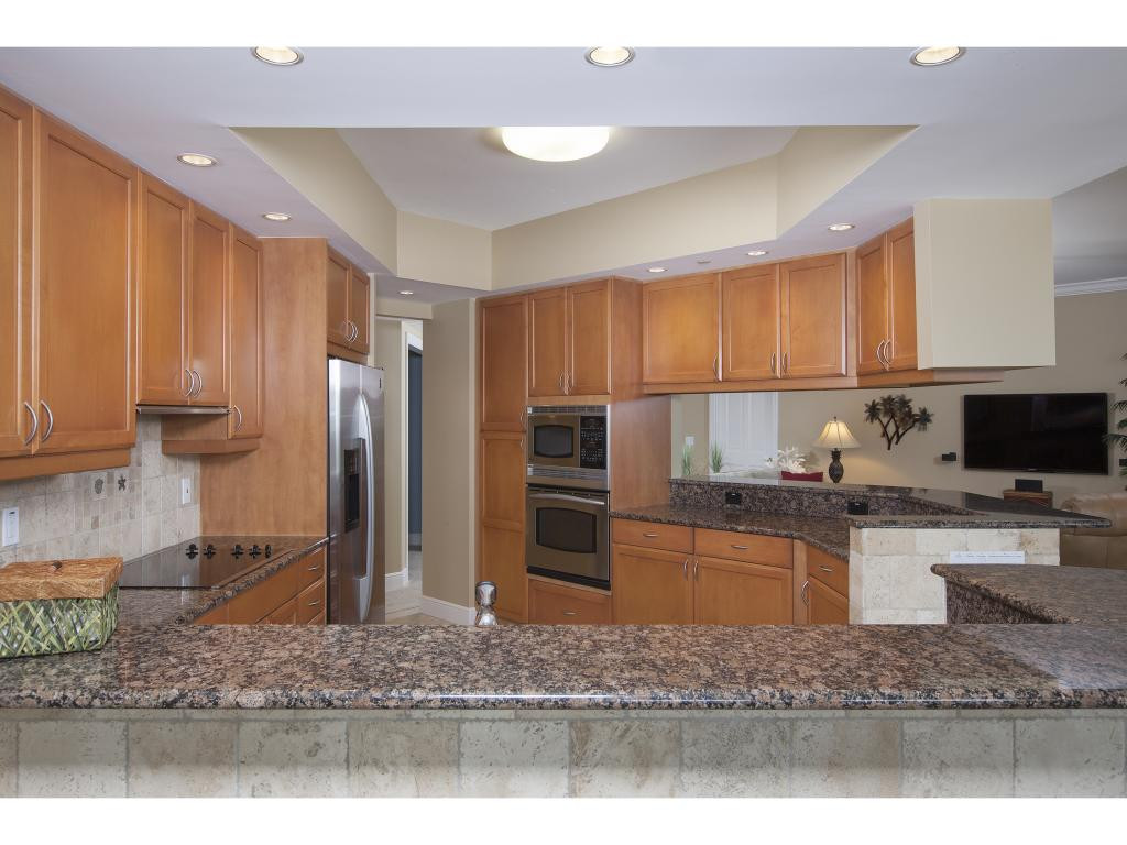 a kitchen with stainless steel appliances wooden cabinets a refrigerator and a sink