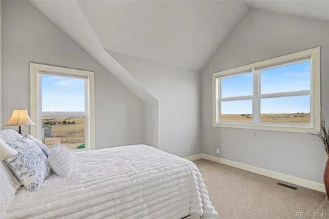 a bedroom with a bed and a large window with the outer view