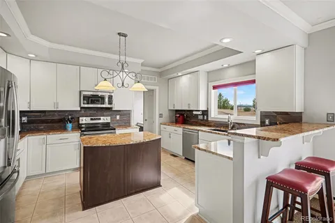 a kitchen with stainless steel appliances granite countertop wooden cabinets a dining table and chairs