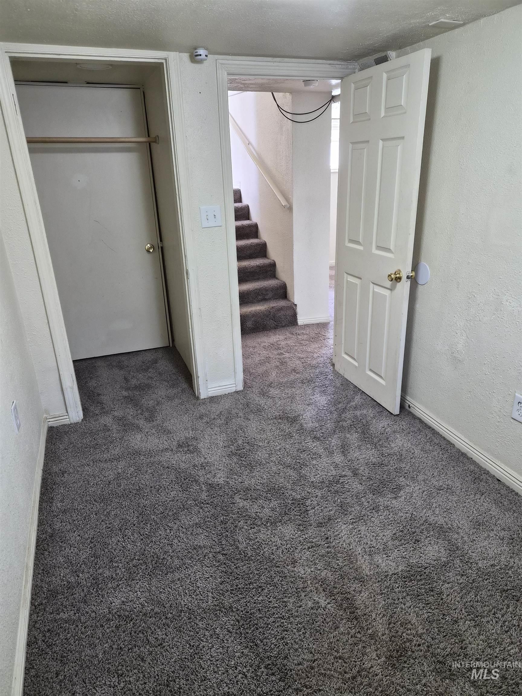 682 Randolph Avenue Pocatello, ID 83201 - Photo 12 of 29 Unfurnished bedroom featuring dark carpet, a textured wall, and a closet
