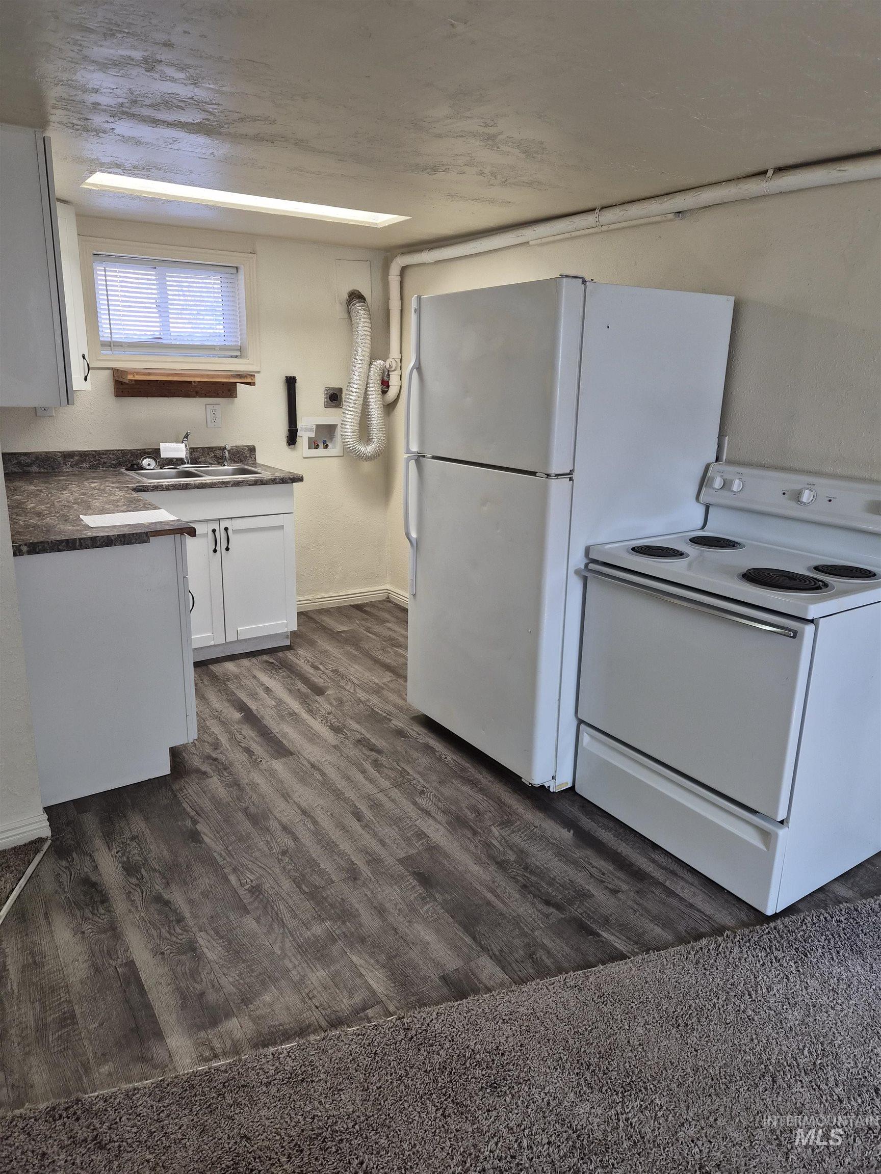 682 Randolph Avenue Pocatello, ID 83201 - Photo 14 of 29 Kitchen with white appliances, dark countertops, dark wood-style floors, and white cabinets