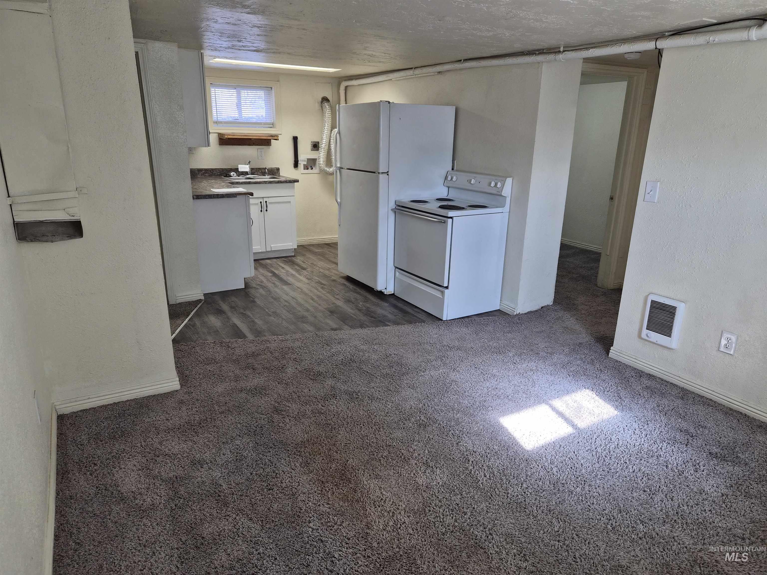 682 Randolph Avenue Pocatello, ID 83201 - Photo 15 of 29 Kitchen featuring white appliances, dark countertops, dark colored carpet, white cabinetry, and a textured wall