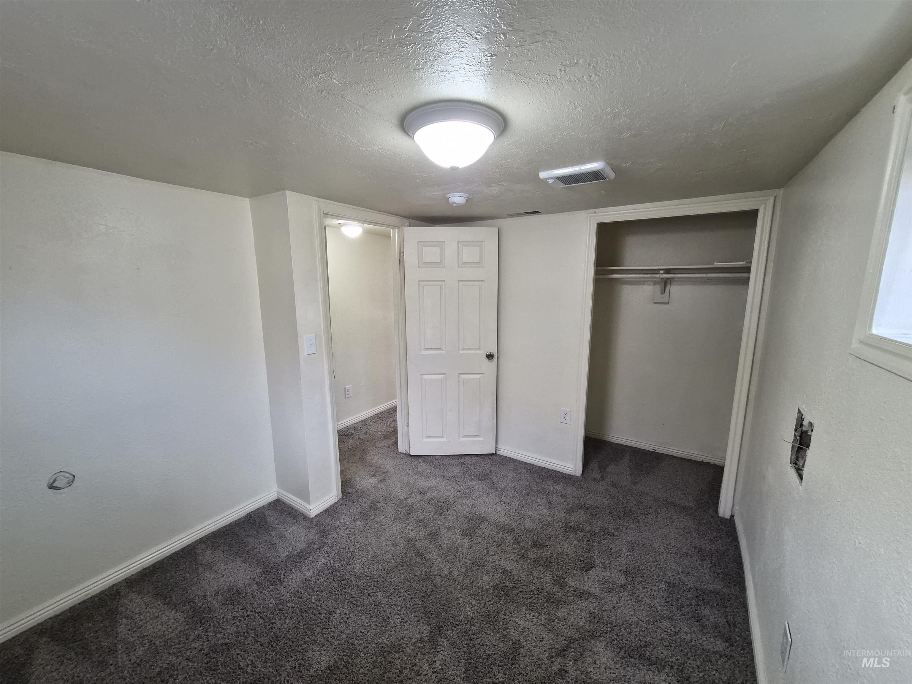 682 Randolph Avenue Pocatello, ID 83201 - Photo 19 of 29 Unfurnished bedroom featuring a textured ceiling, a closet, and dark colored carpet