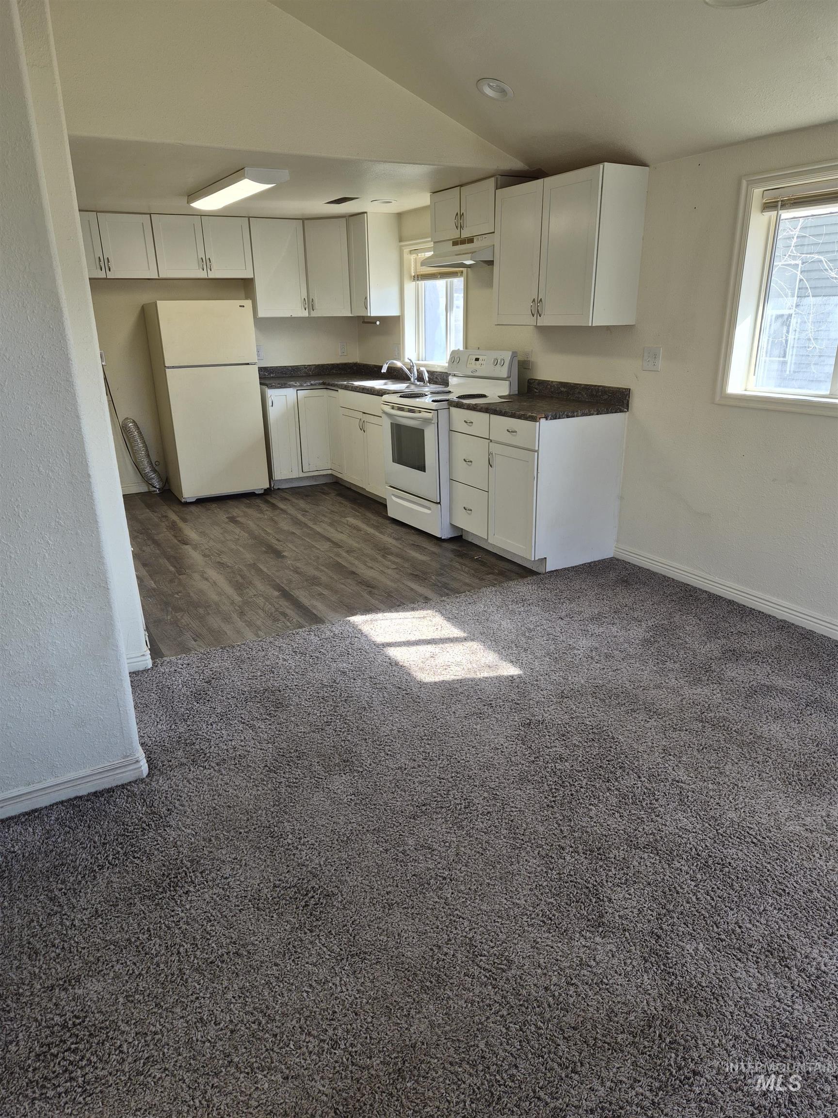 682 Randolph Avenue Pocatello, ID 83201 - Photo 2 of 29 Kitchen with dark countertops, white cabinetry, white appliances, dark carpet, and lofted ceiling