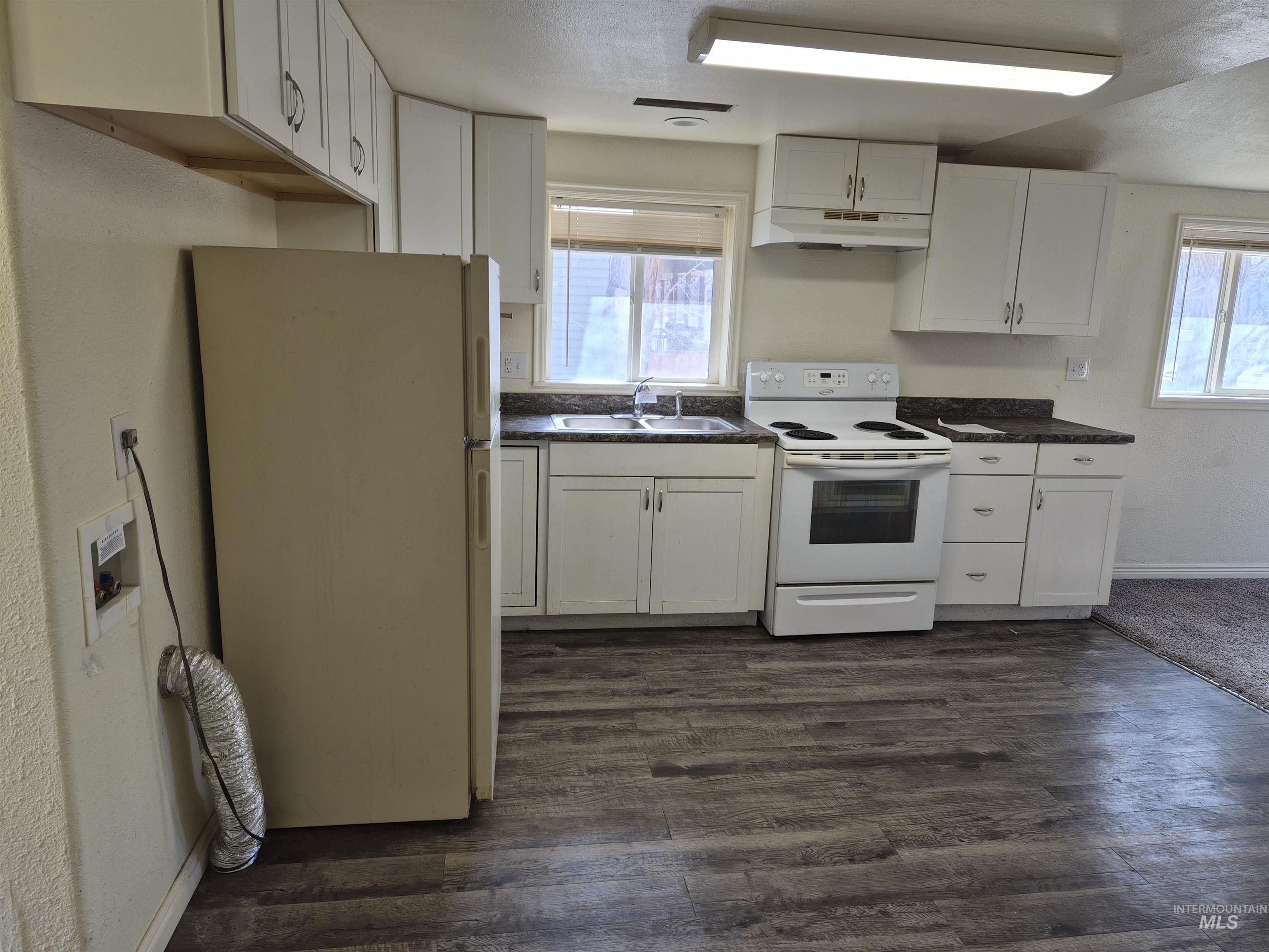 682 Randolph Avenue Pocatello, ID 83201 - Photo 3 of 29 Kitchen featuring white appliances, white cabinetry, healthy amount of natural light, and dark countertops