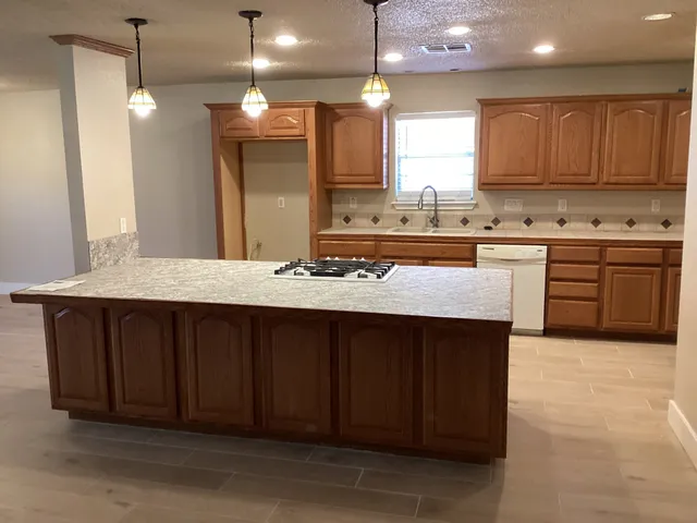 a kitchen with kitchen island granite countertop wooden cabinets and a sink