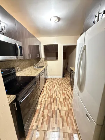 a kitchen with stainless steel appliances granite countertop a refrigerator and a stove