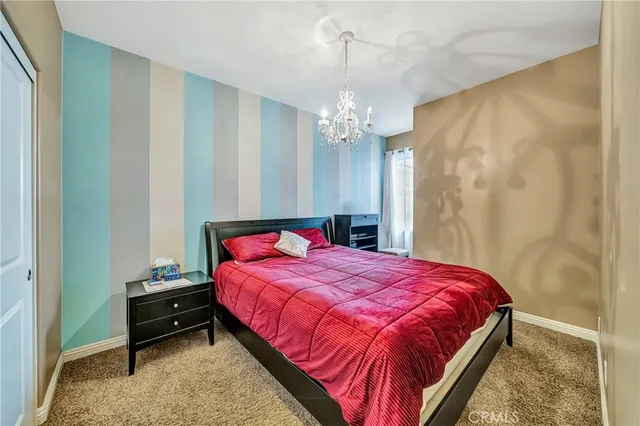 a bedroom with a bed a flat screen tv and a chandelier