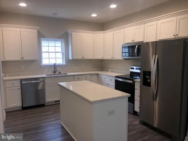 a kitchen with a sink a refrigerator a window and cabinets