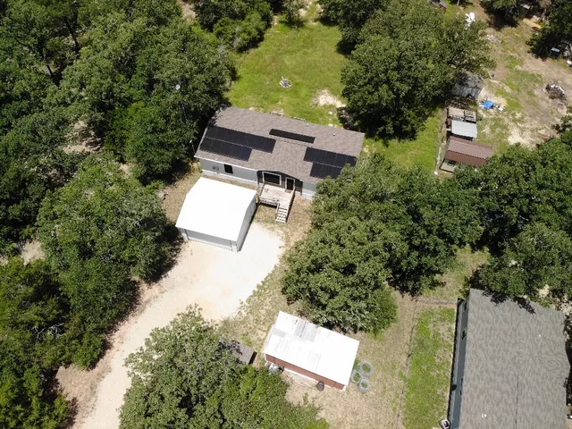 an aerial view of residential house with outdoor space and trees all around