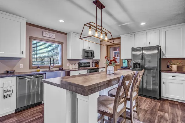 a kitchen with stainless steel appliances granite countertop a kitchen island hardwood floor sink stove dining table and chairs