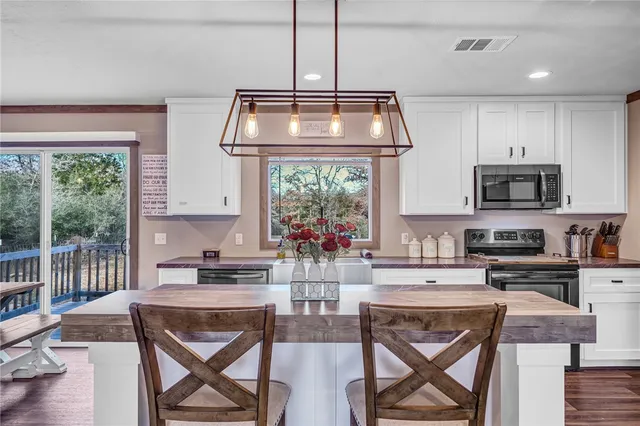 a kitchen with stainless steel appliances granite countertop a stove a sink dishwasher a dining table and chair with wooden floor