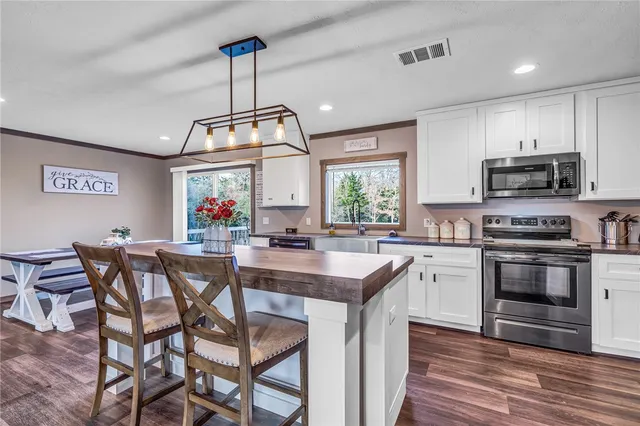 a kitchen with stainless steel appliances a kitchen island hardwood floor sink stove dining table and chairs