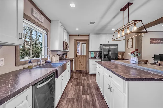 a kitchen with granite countertop a sink a counter space appliances and cabinets