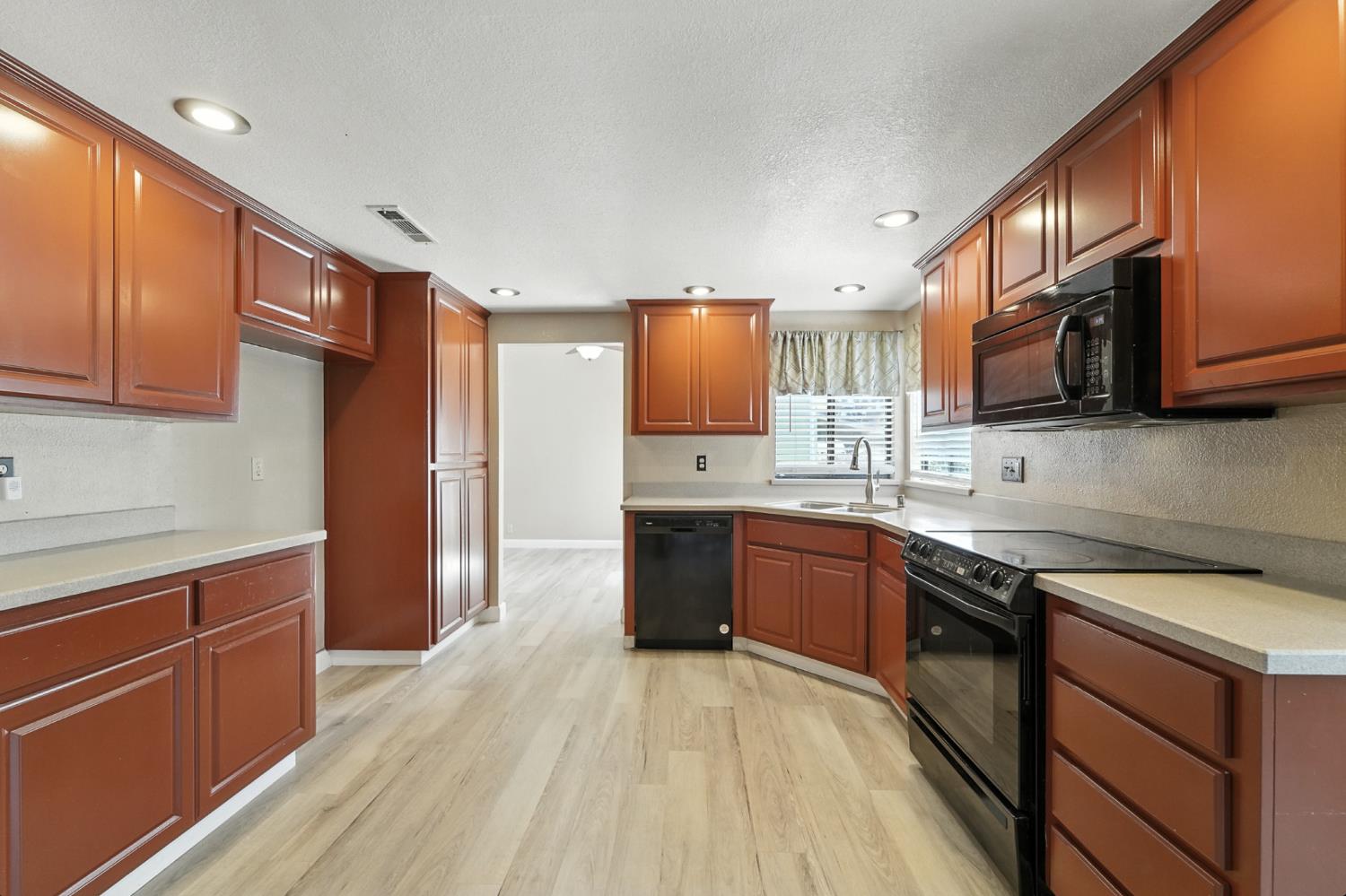 834 Cedar Ridge Drive Turlock, CA 95382 - Photo 19 of 57 a kitchen with stainless steel appliances granite countertop wooden cabinets a refrigerator a sink a stove a microwave and wooden floors