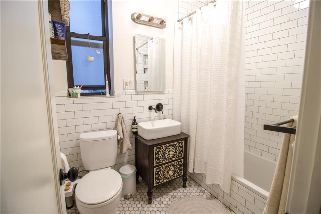 1701 Albemarle Road, Unit A10 Brooklyn, NY 11226 - Photo 12 of 16 a bathroom with a toilet a sink and a mirror