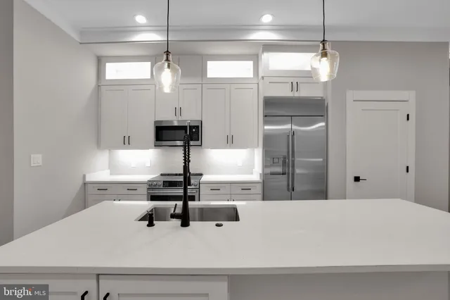 a kitchen with a refrigerator a sink and white cabinets