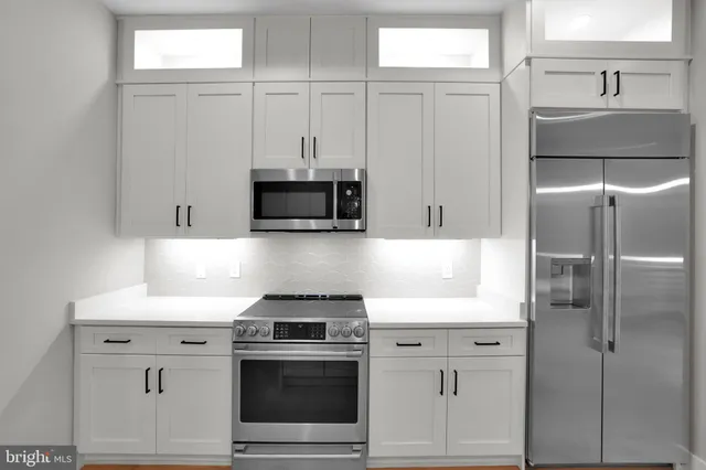 a kitchen with stainless steel appliances white cabinets and a refrigerator