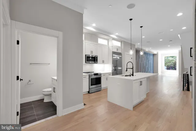 a large white kitchen with a stove a sink dishwasher and a refrigerator with wooden floor