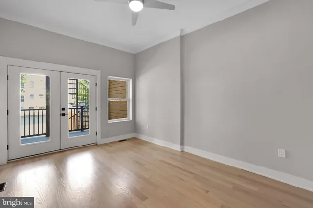 a view of an empty room with wooden floor and a window