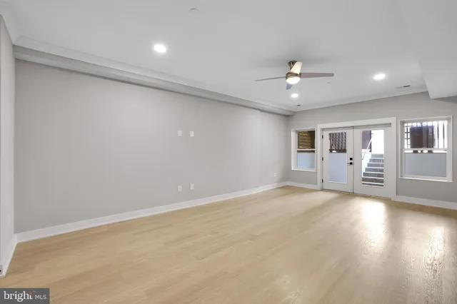 an empty room with chandelier fan and windows