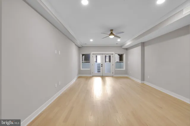 a view of empty room with wooden floor and fan