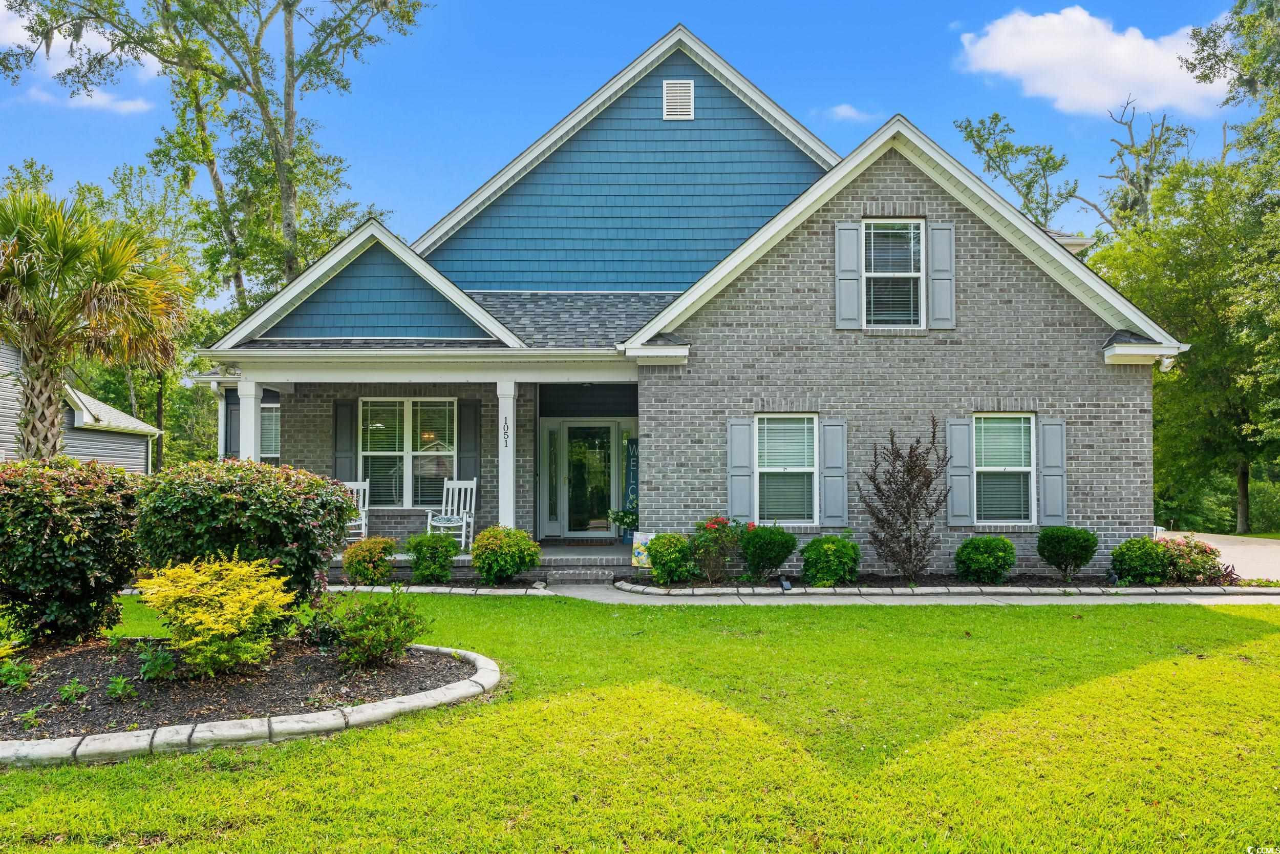 Craftsman inspired home with a porch, brick siding, and a front lawn