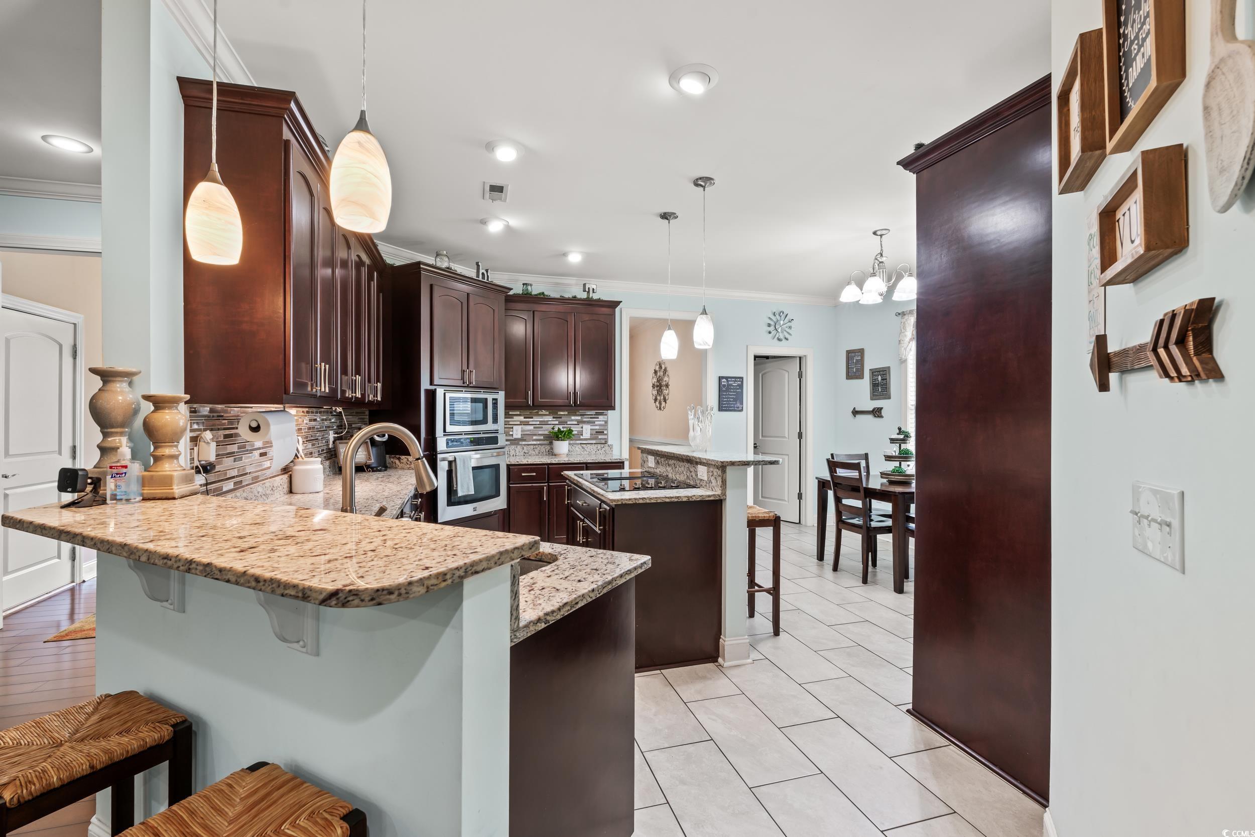 1051 Academy Drive Conway, SC 29526 - Photo 6 of 37 Kitchen featuring stainless steel appliances, ornamental molding, a kitchen bar, a peninsula, and decorative backsplash